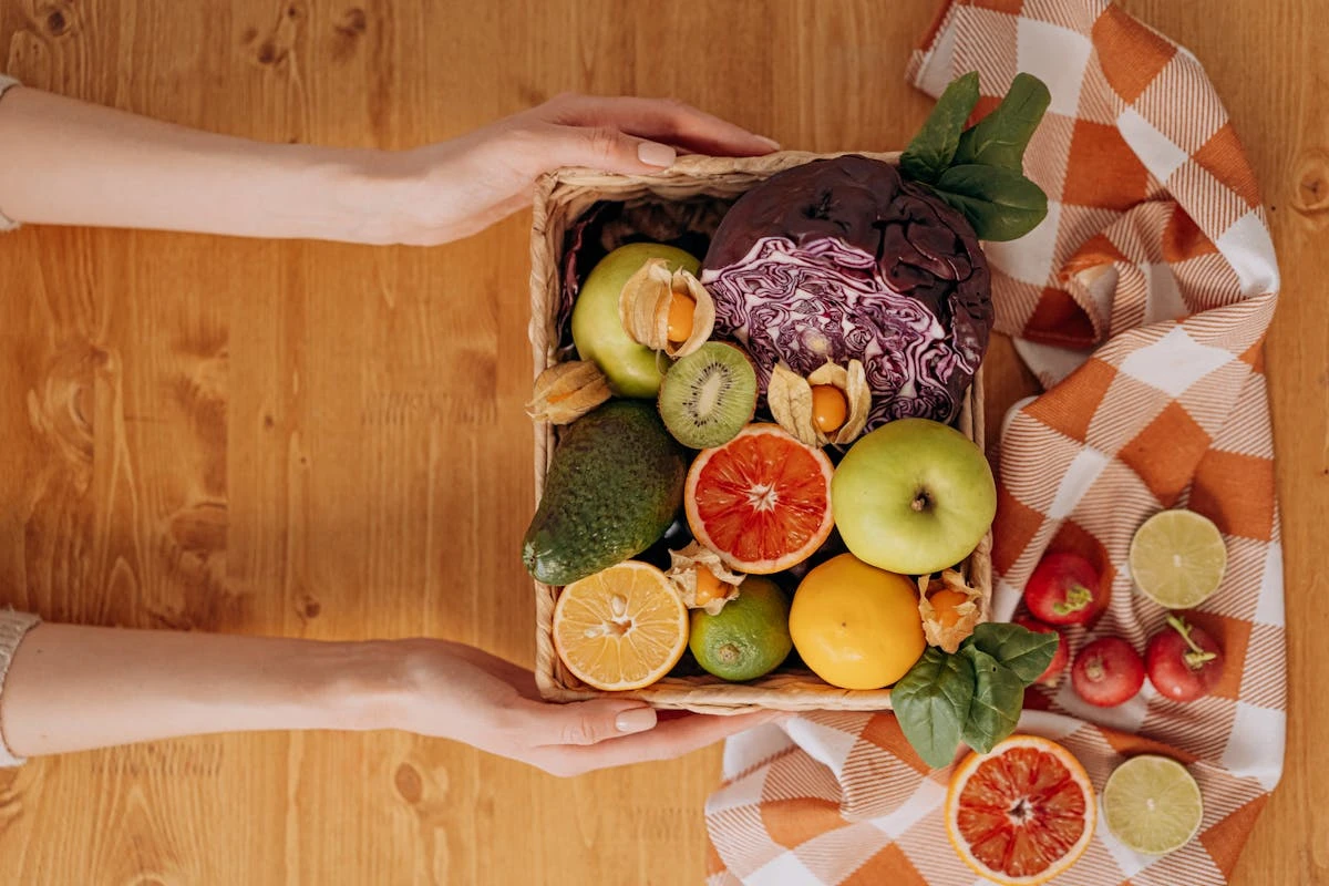 Korb mit Gemüse und Obst wie Rotkohl, Äpfeln, Orangen, Radieschen usw.