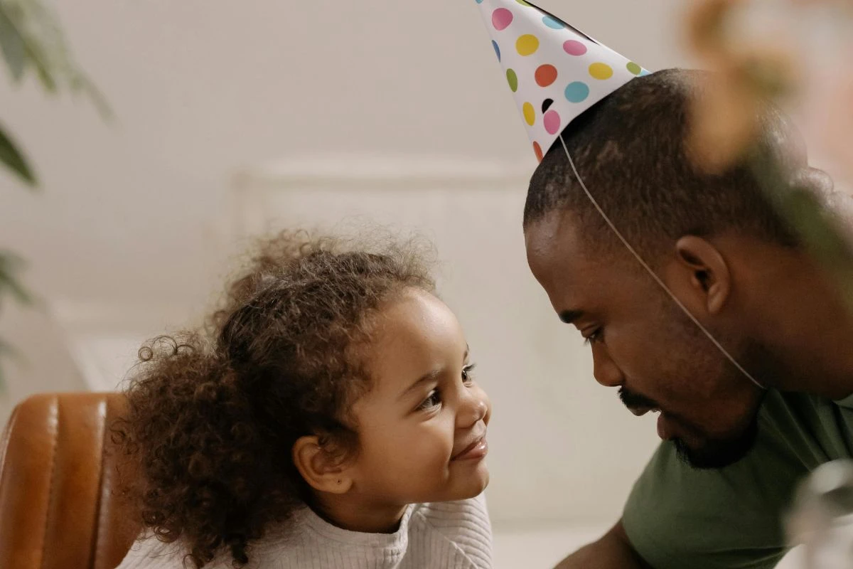 Vater mit Partyhütchen und Tochter feiern Vatertag