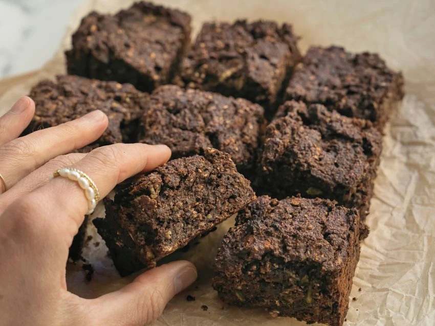 Eine Hand greift auf eine Reihe Schoko-Brownies zu.